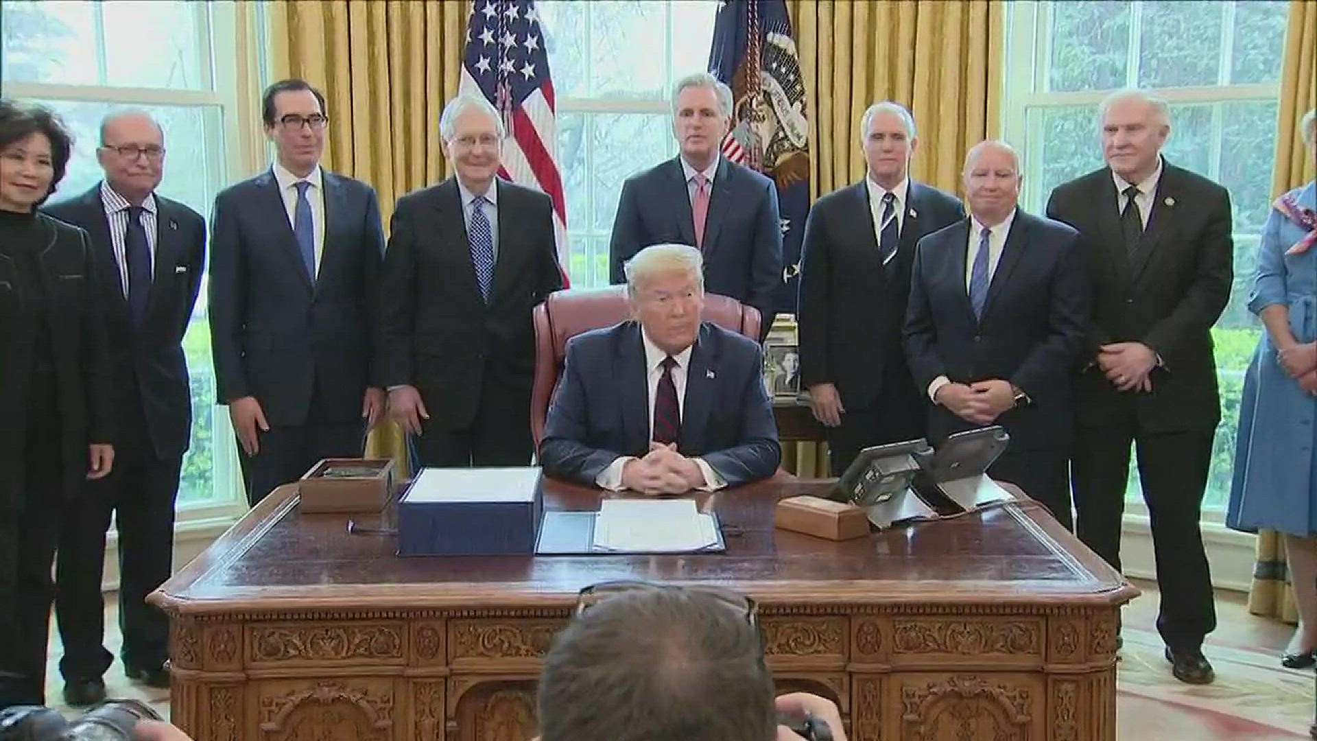 President Donald Trump on Friday signed the $2 trillion coronavirus economic stimulus bill in an Oval Office ceremony.