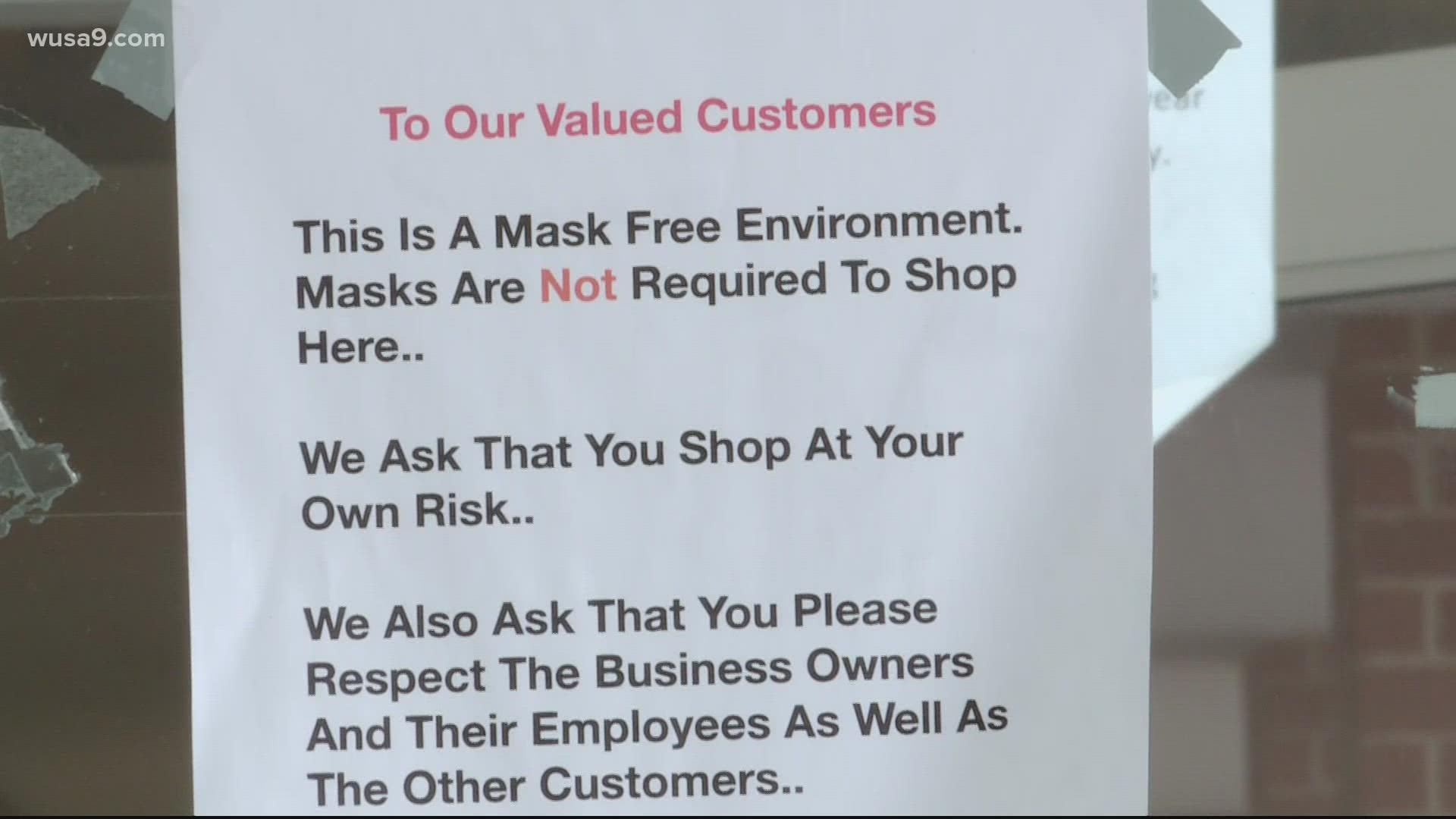 A sign above the main entrance reads "This is a mask free environment." and asks customers to shop at their own risk.