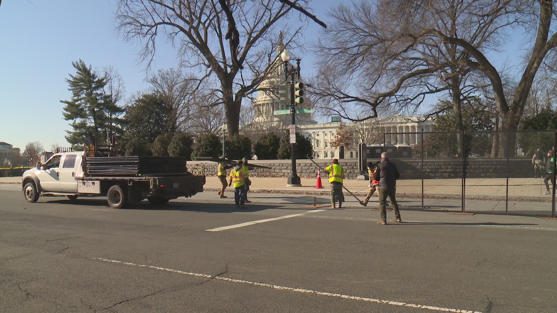 Nearly a day after pro-Trump mob swarmed the Capitol, police build fencing to the protect the grounds.